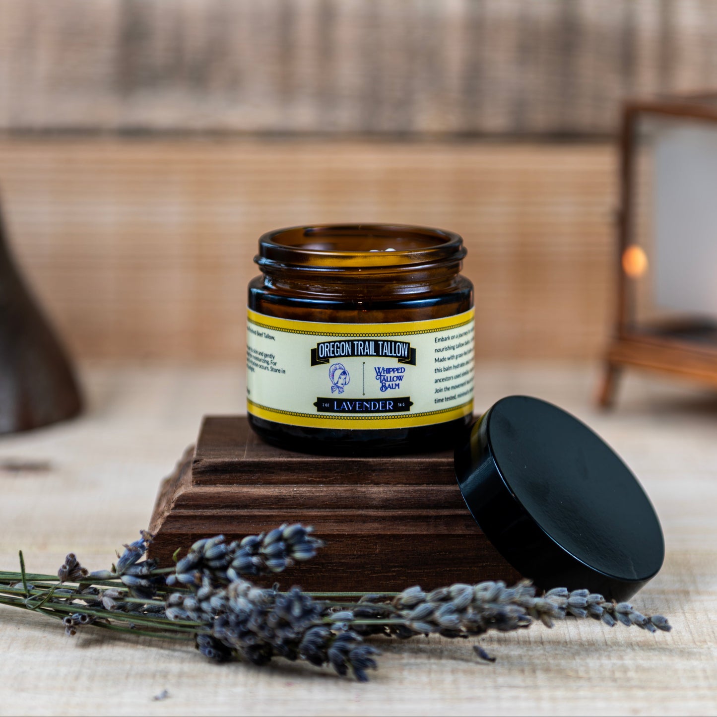 Jar of lavender product on a wooden block with lavender flowers and a rustic background